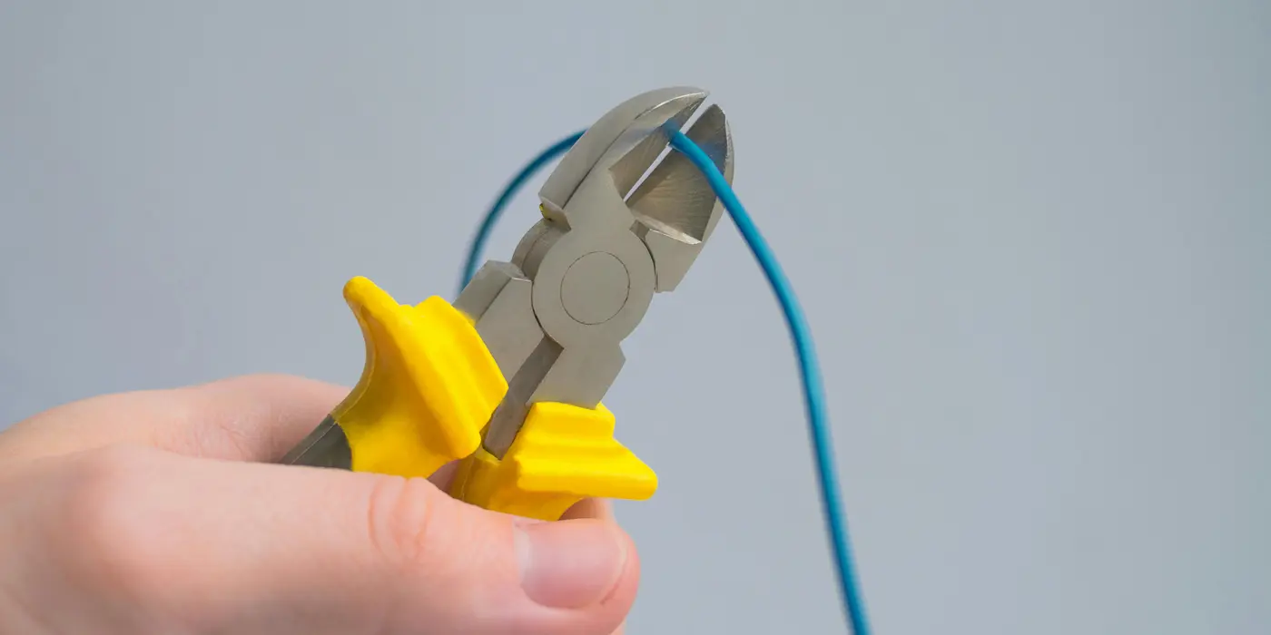 a hand using a pair of pliers to cut a wire from Electrician Richardson TX in Richardson, TX - Electrical panel upgrades